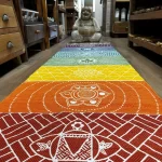 Colourful runner rug featuring chakra symbols laid on a floor leading towards a laughing Buddha statue