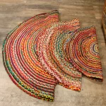 Three colourful circular braided jute and fabric rugs layered on a wooden floor