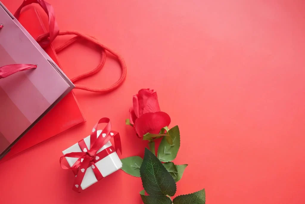Red gift box and rose on a vibrant red background. Perfect for celebrations.